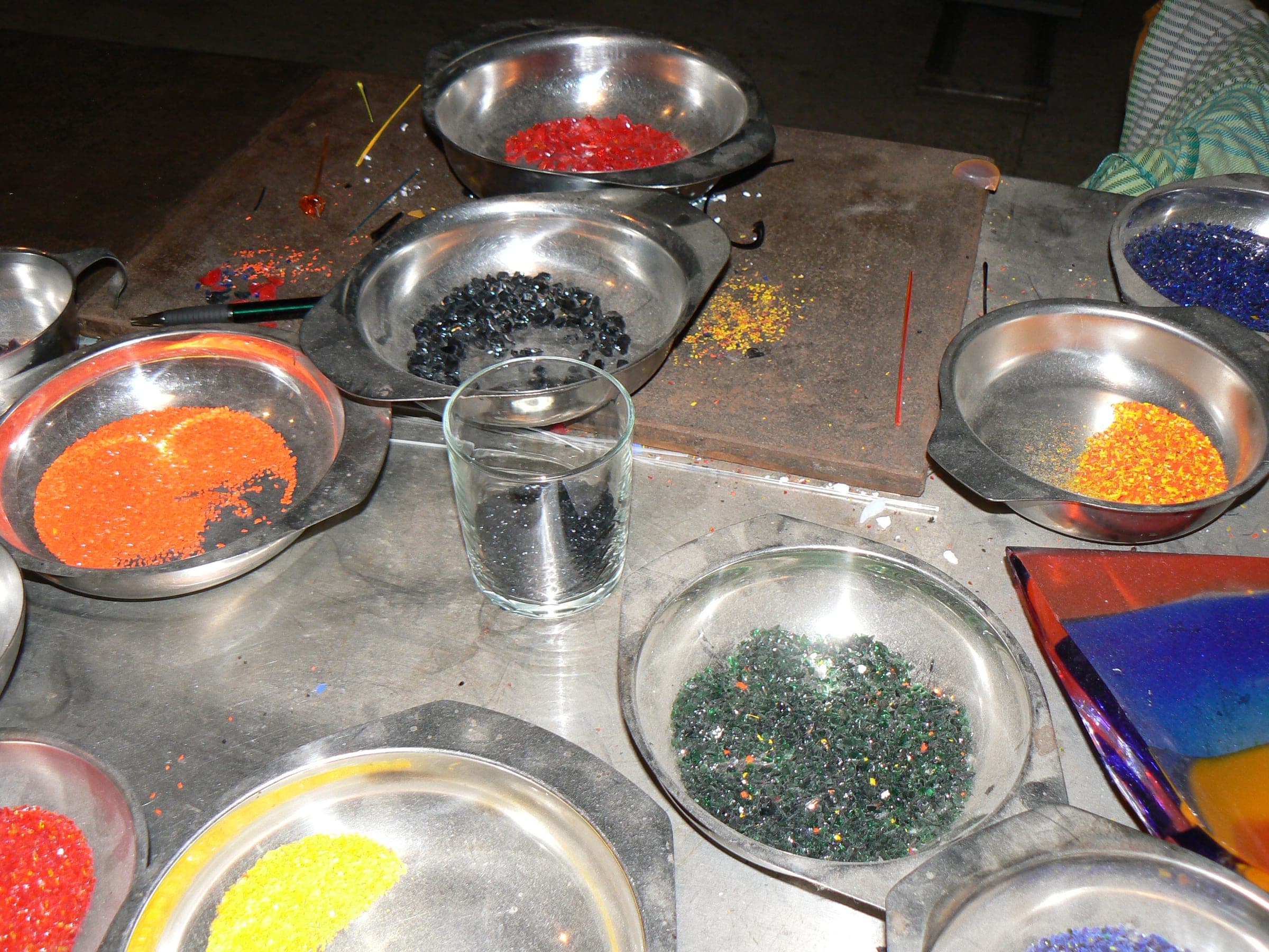 A glassblower's bench with bowls of coloured glass frit