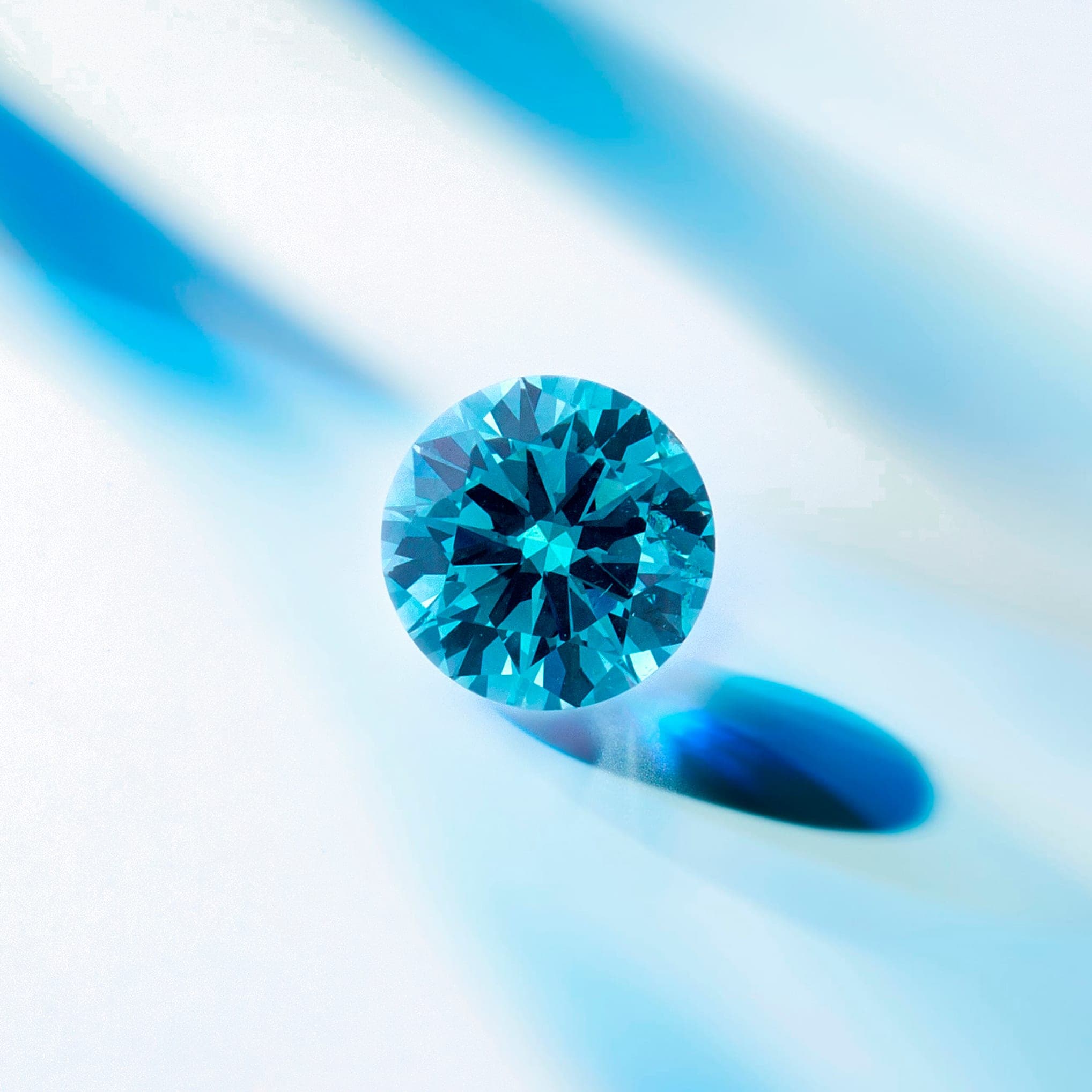 A blue laboratory-grown diamond, brilliant cut, on a white background